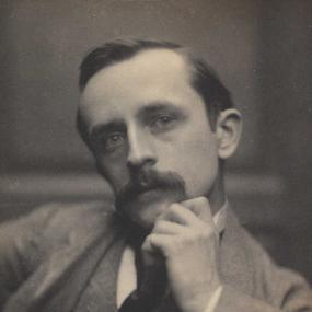 Photograph of James Barrie, not yet a baron, by Frederick Hollyer, 1892. Barrie sits, wearing a coat, jacket, and waistcoat, with his head tilted to one side and chin resting on his left hand.