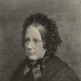 Photo of Georgiana Fullerton. She is wearing a dark, feathery bonnet tied with a large dark bow under her chin, and a dark shawl.